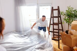 Couple protecting furniture before home painting